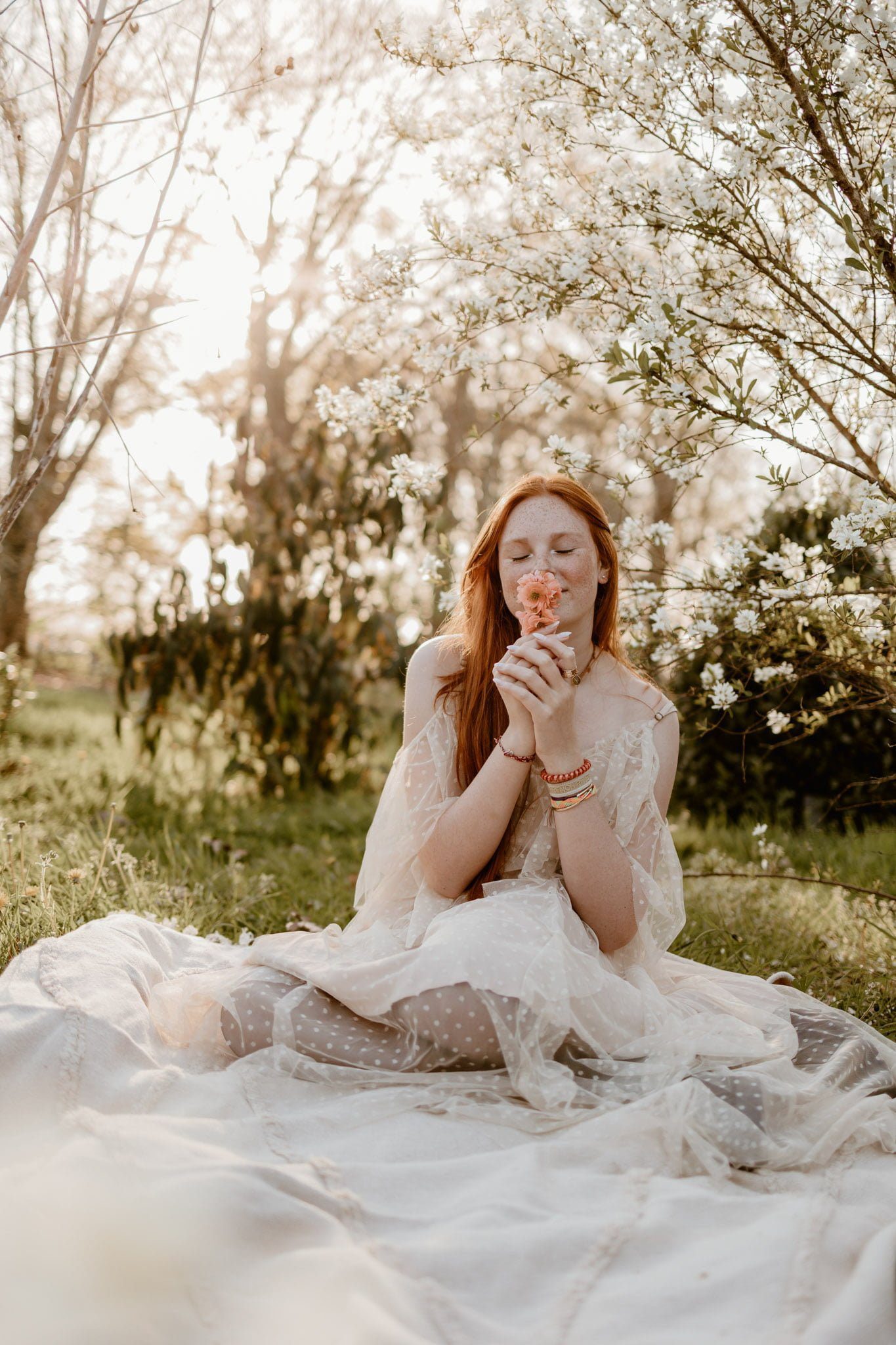Jeune fille rousse qui respire une fleur orange, entourée de fleurs blanches - marine delforge - photographe à Pau